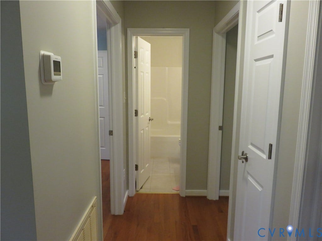14 N Kalmia Avenue, Henrico, VA 23075 Interior hallway featuring wood-finish flooring, white paneled doors, neutral wall paint, and a programmable wall-mounted thermostat