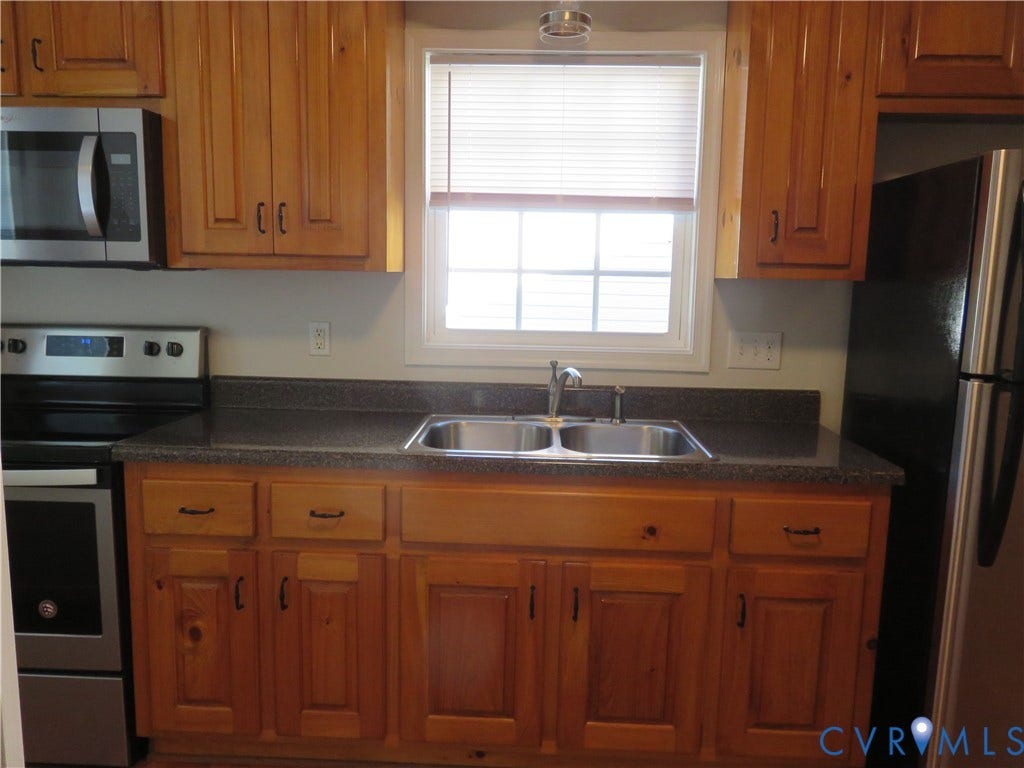 14 N Kalmia Avenue, Henrico, VA 23075 Kitchen featuring natural-finish wood cabinetry, solid-surface countertops, stainless steel appliances, and a dual-basin sink with a gooseneck faucet