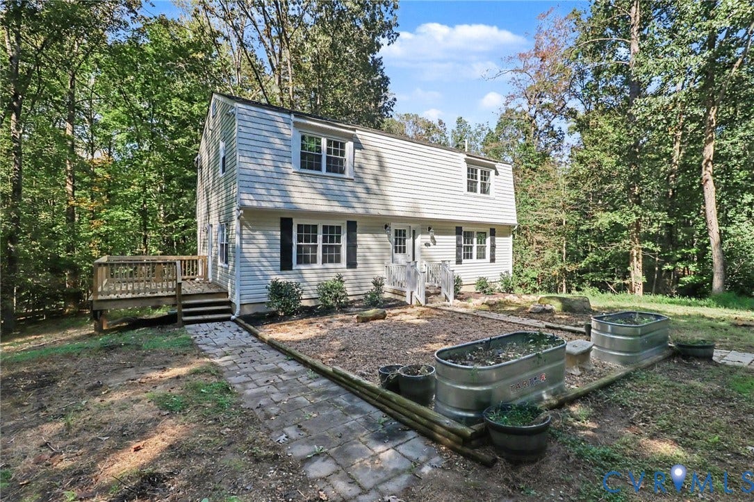 2511 Mill Road, Powhatan, VA 23139 Two-story residence with horizontal siding, a raised wood deck, stone paver pathway, and galvanized steel garden beds situated on a wooded lot
