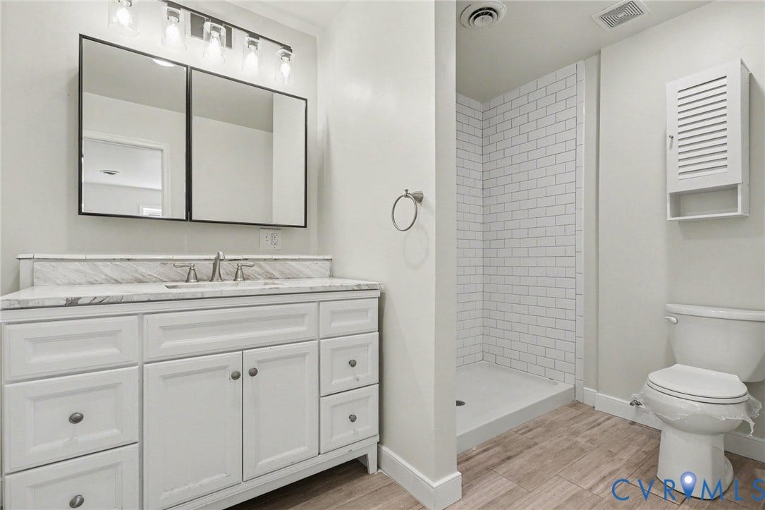2511 Mill Road, Powhatan, VA 23139 White shaker-style vanity with stone-top surface, dual-panel medicine cabinet, walk-in shower with white subway tile surround, and wood-finish flooring