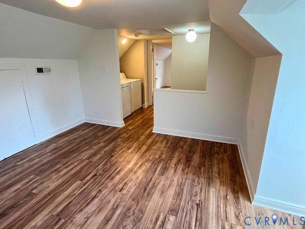 Interior space featuring LVP flooring, vaulted ceilings, built-in storage cabinetry, and integrated laundry appliances