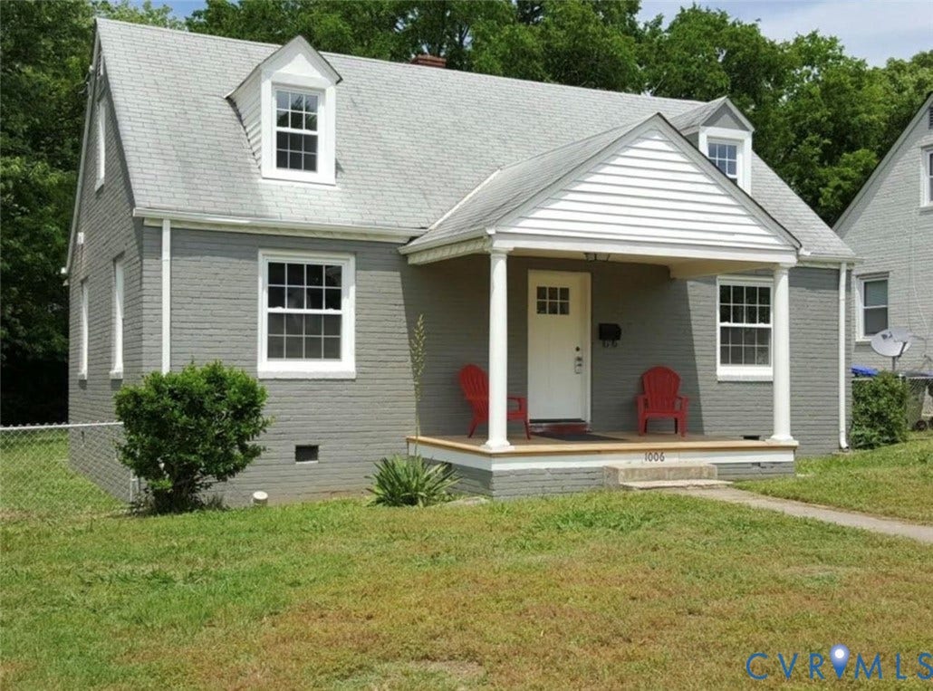 Cape Cod exterior featuring a painted brick facade, covered front porch with column supports, and two dormer windows