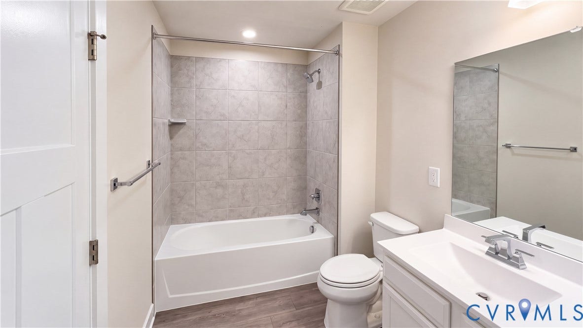 11500 Amara Drive, Chesterfield, VA 23838 Bathroom featuring a vanity with an integrated sink, rectangular wall mirror, tub-shower combination with ceramic tile surround, and wood-finish flooring