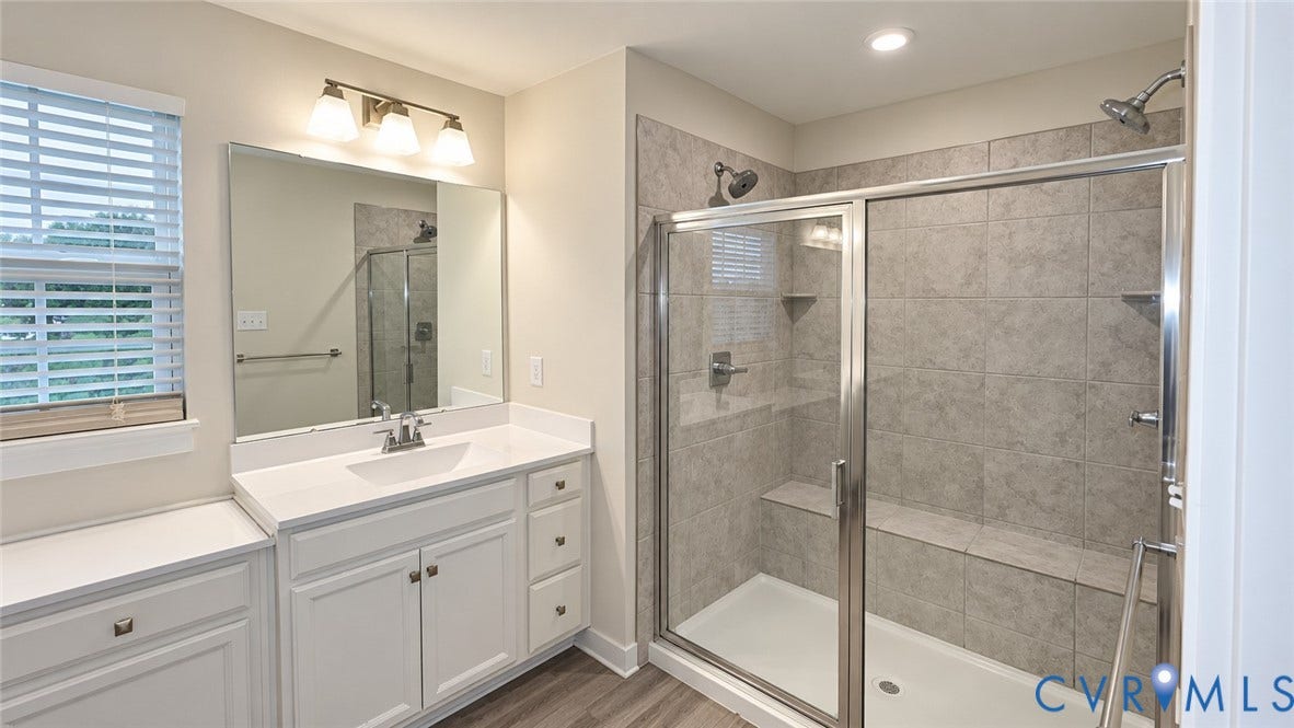 11500 Amara Drive, Chesterfield, VA 23838 Bathroom featuring a walk-in shower with tile surround and built-in bench, vanity with white countertop, integrated sink, and wood-finish flooring