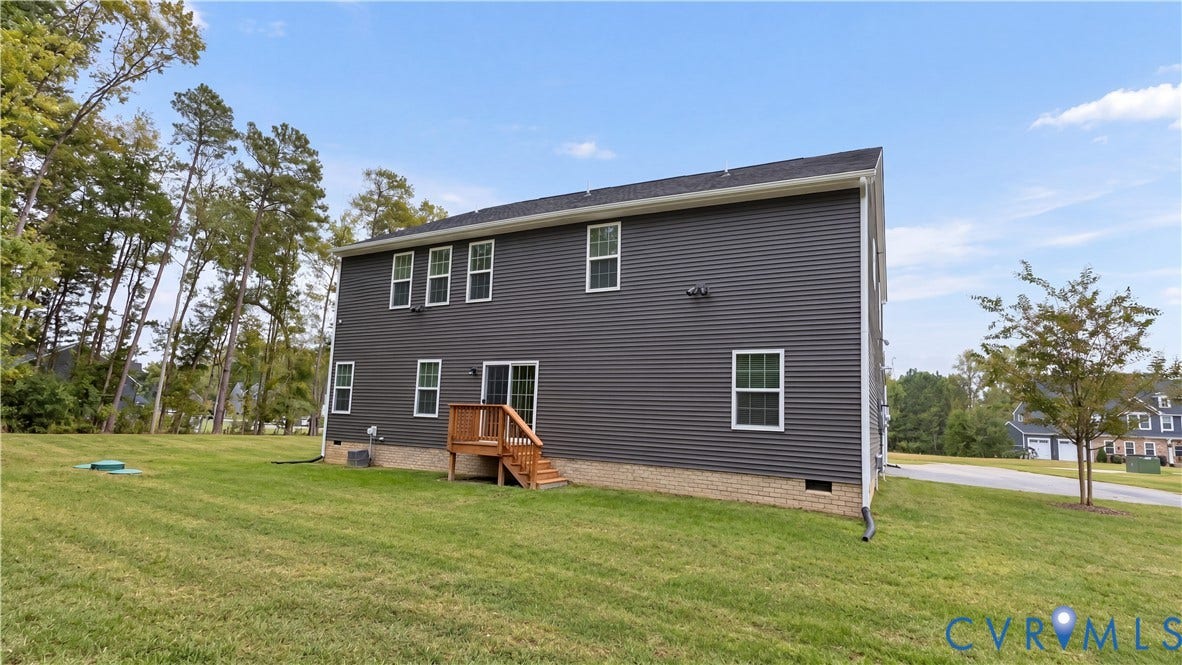 11500 Amara Drive, Chesterfield, VA 23838 Dark-toned siding exterior featuring a stone-veneer foundation, rear wood deck, and expansive lawn with mature tree line