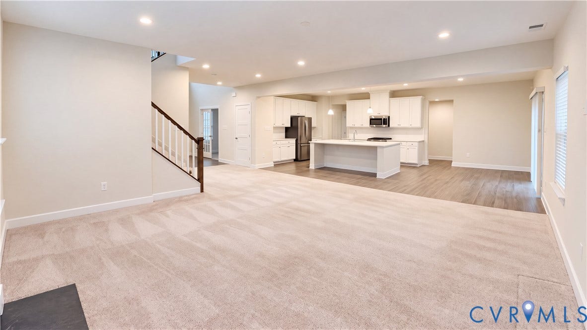 11500 Amara Drive, Chesterfield, VA 23838 Open-concept interior featuring a kitchen with white cabinetry and a center island, wood-finish flooring, recessed lighting, and a staircase with a wooden handrail
