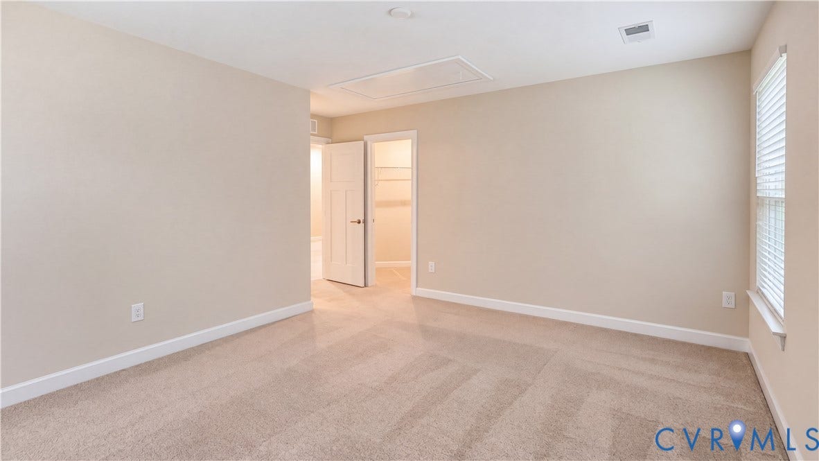 11500 Amara Drive, Chesterfield, VA 23838 Neutral-toned room with plush wall-to-wall carpeting, window with slatted blinds, and an interior doorway providing access to a walk-in closet with built-in shelving
