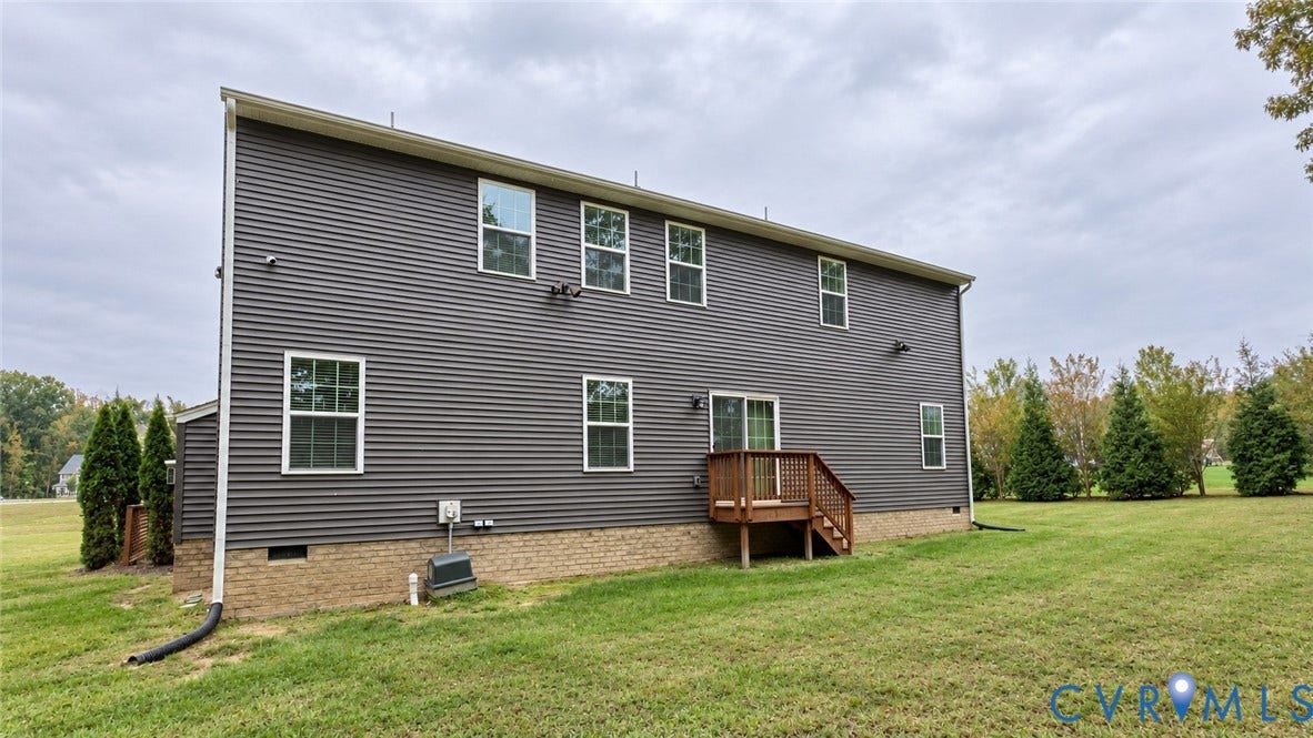 11500 Amara Drive, Chesterfield, VA 23838 Dark horizontal siding exterior featuring a brick foundation, wood-framed rear deck, sliding glass door, and expansive lawn