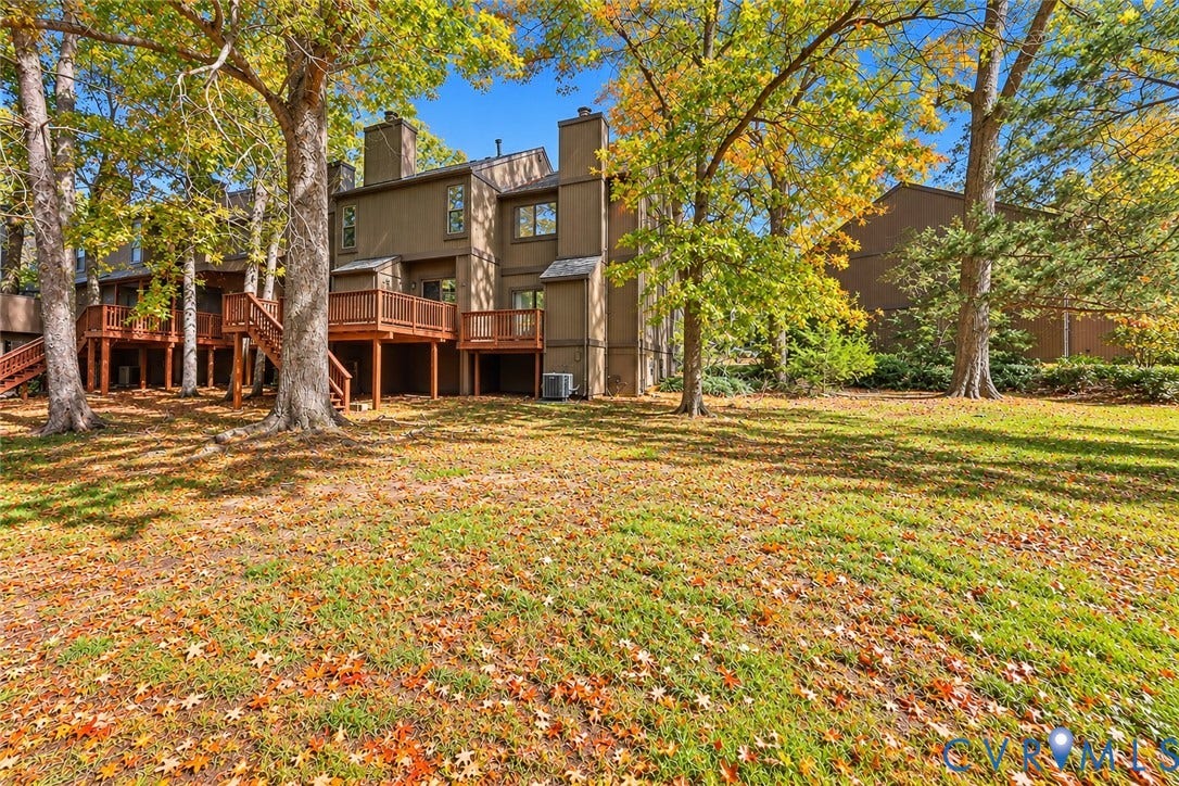 11947 W Briar Patch Drive, Chesterfield, VA 23113 Multi-story exterior featuring wood siding, elevated wood decking, brick chimneys, and mature trees across the surrounding landscape