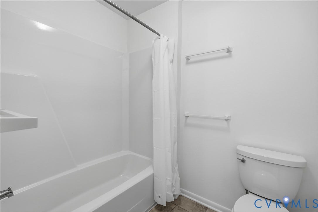 11947 W Briar Patch Drive, Chesterfield, VA 23113 Full bathroom featuring a tub-shower combination with integrated wall surround, dual chrome wall-mounted towel bars, and a white porcelain toilet