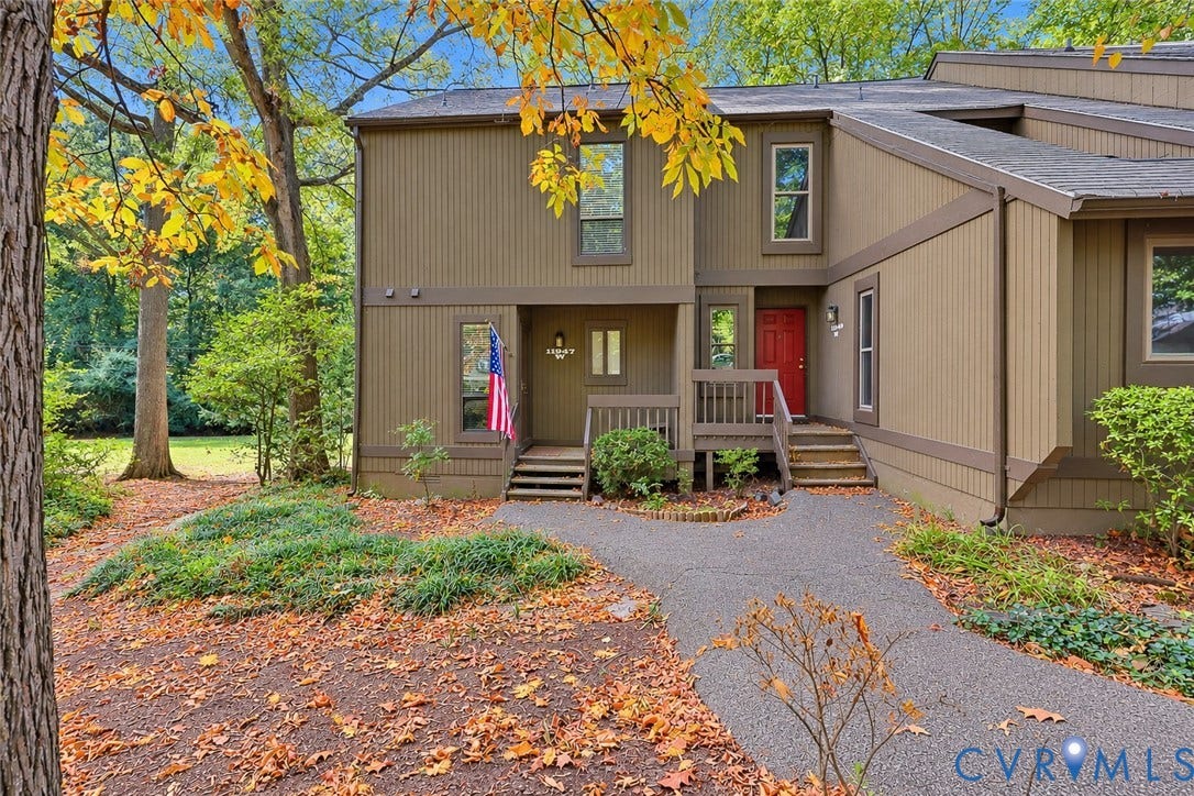 11947 W Briar Patch Drive, Chesterfield, VA 23113 Vertical wood siding exterior featuring a paved walkway, raised wood-frame deck, and mature surrounding landscape