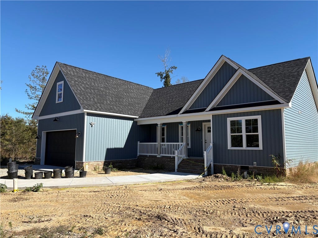 15135 Lebanon, Parson's Retreat, Disputanta, VA 23842 Blue vertical siding exterior featuring a multi-gabled roofline, stone veneer foundation, covered front porch with a white railing, and an attached two-car garage