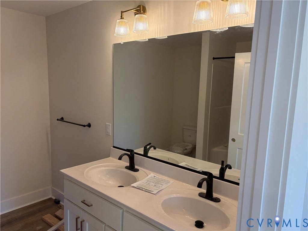 15135 Lebanon, Parson's Retreat, Disputanta, VA 23842 Double vanity featuring white cabinetry, integrated sinks, dark metal fixtures, and an expansive wall-mounted mirror accented by multi-bulb vanity lighting