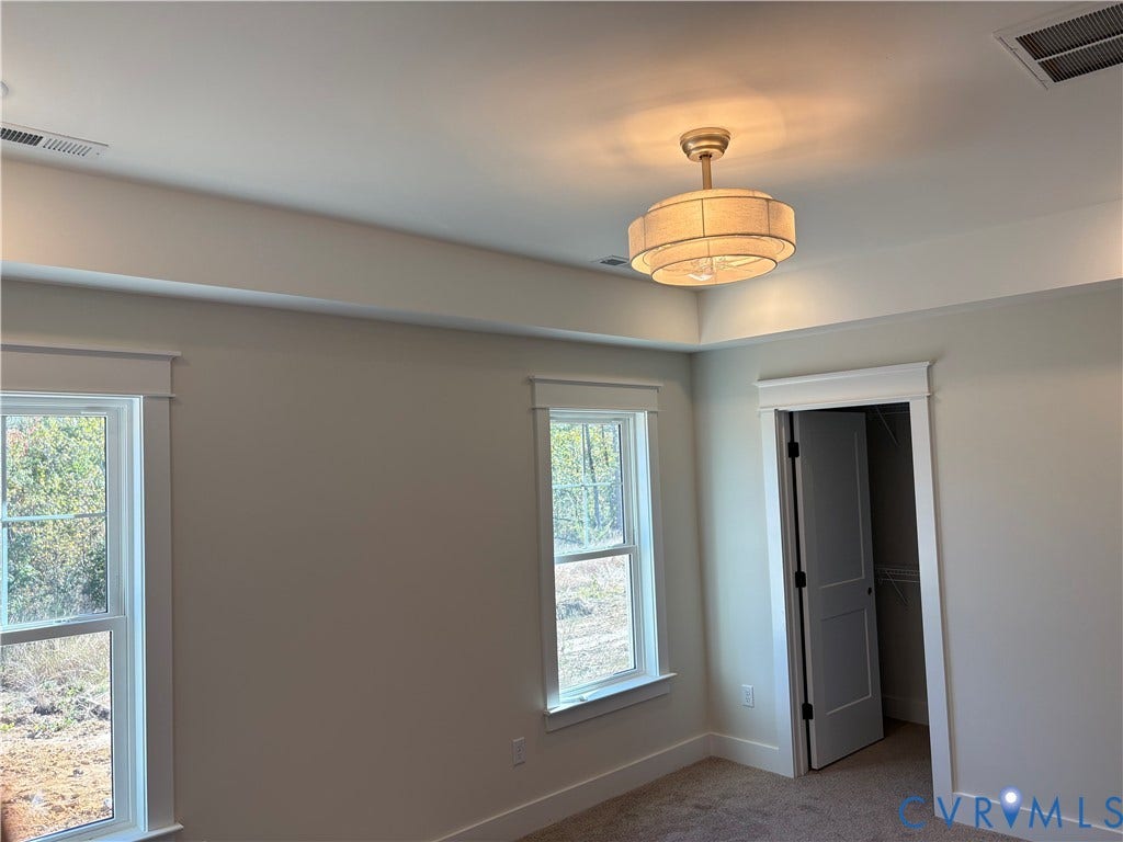 15135 Lebanon, Parson's Retreat, Disputanta, VA 23842 Tray ceiling with a multi-tiered fabric drum light fixture, windows with heavy casing, and a walk-in closet featuring a paneled door