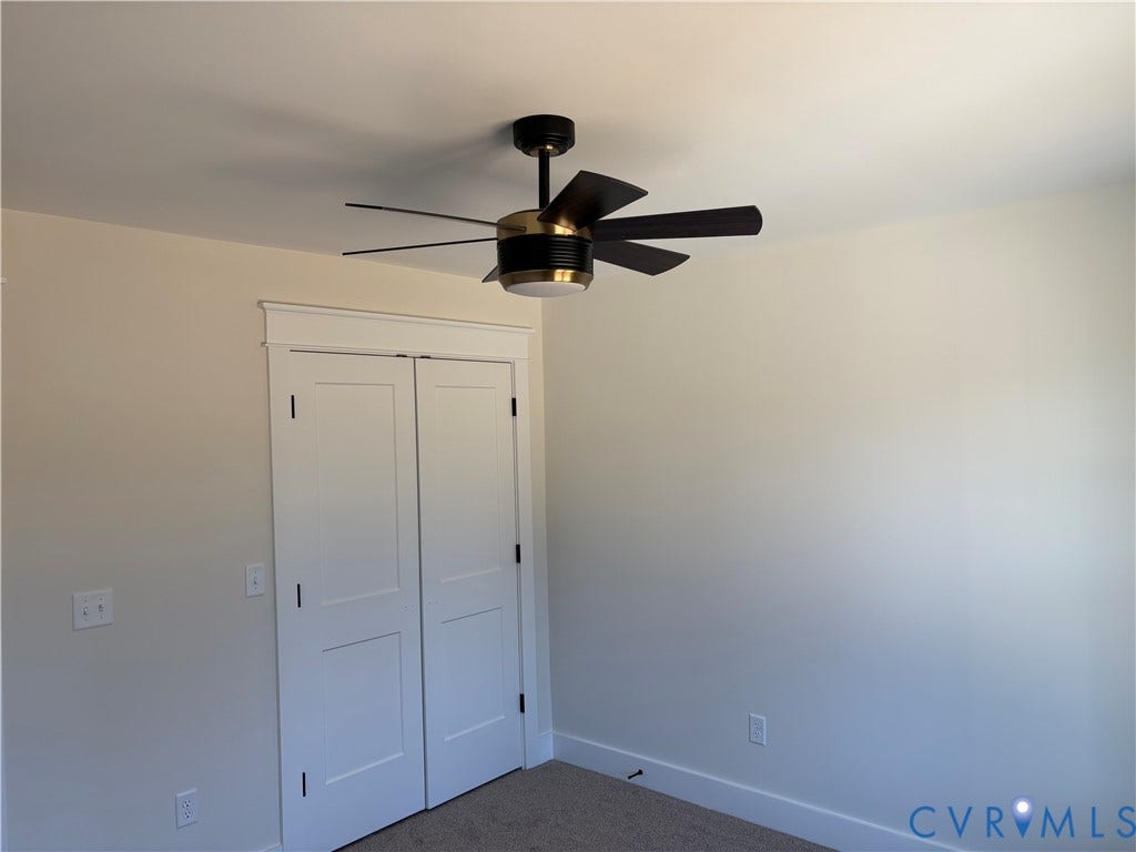 15135 Lebanon, Parson's Retreat, Disputanta, VA 23842 Modern ceiling fan with integrated light fixture and metallic housing, double-panel closet doors featuring decorative header trim, and neutral wall-to-wall carpeting