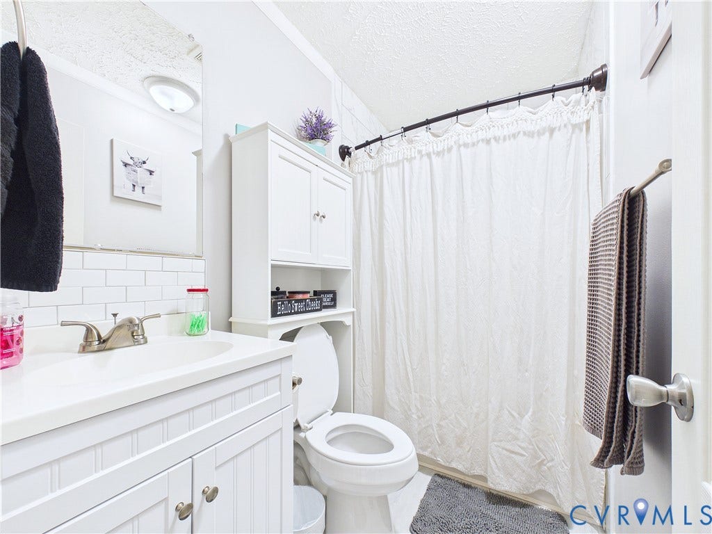 290 Western Lane, Appomattox, Appomattox, VA 24522 White vanity featuring a beadboard facade, rectangular basin, dual-handle faucet, and white subway tile backsplash, complemented by an integrated over-the-toilet storage cabinet