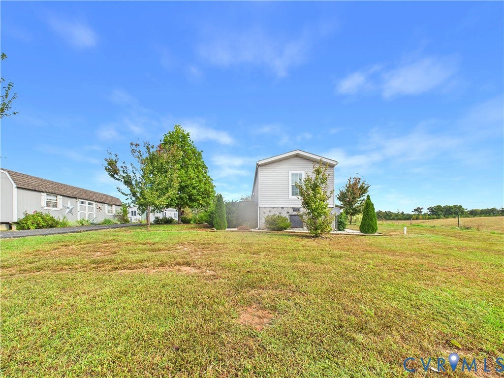 290 Western Lane, Appomattox, Appomattox, VA 24522 Expansive exterior grounds featuring a manicured lawn, a detached storage building, stone-pattern foundation skirting, and mature landscaping