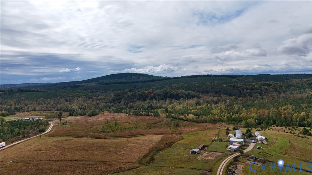 290 Western Lane, Appomattox, Appomattox, VA 24522 Expansive acreage featuring rolling open fields, scattered mature trees, winding gravel paths, and a prominent mountain backdrop