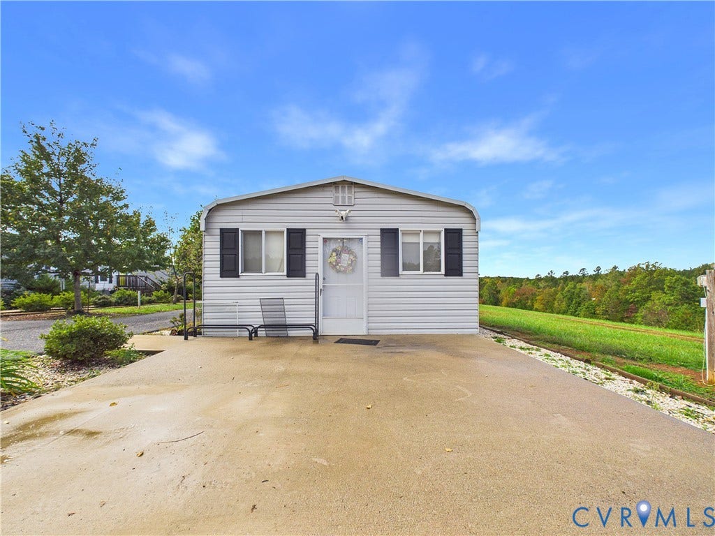 290 Western Lane, Appomattox, Appomattox, VA 24522 Single-story residence featuring light-toned horizontal siding, dark decorative shutters, a central entrance, and a concrete driveway