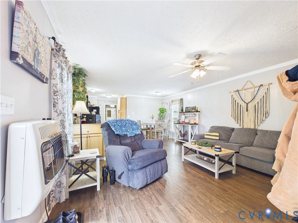 290 Western Lane, Appomattox, Appomattox, VA 24522 Open-concept interior featuring wood-finish flooring, a white wall-mounted gas heater, and a multi-blade ceiling fan with integrated lighting
