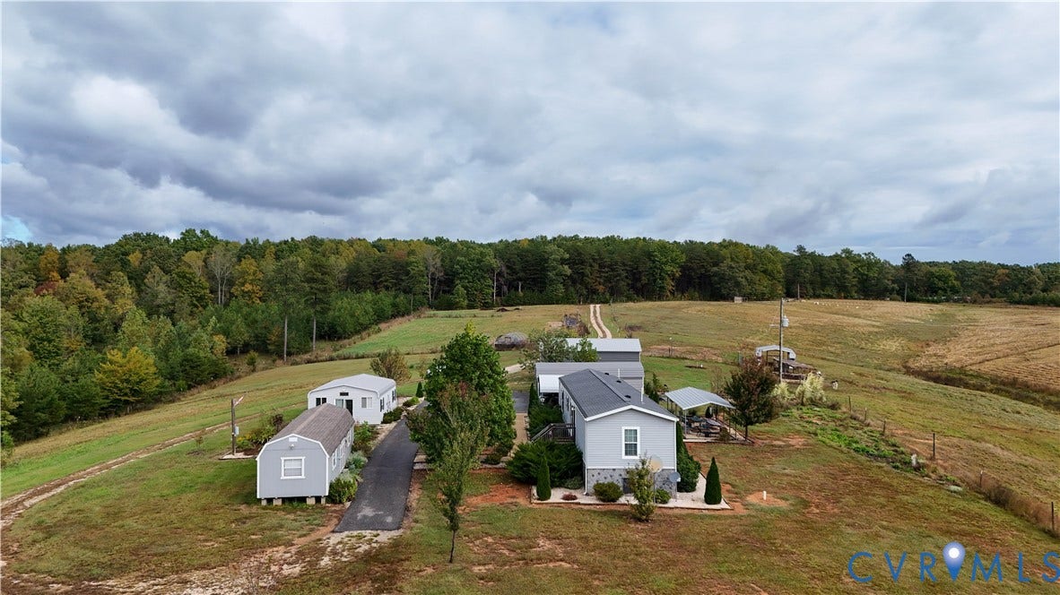 290 Western Lane, Appomattox, Appomattox, VA 24522 Expansive acreage featuring a paved driveway, multiple detached structures, a metal-roofed residence, and extensive open pasture land bordered by mature trees
