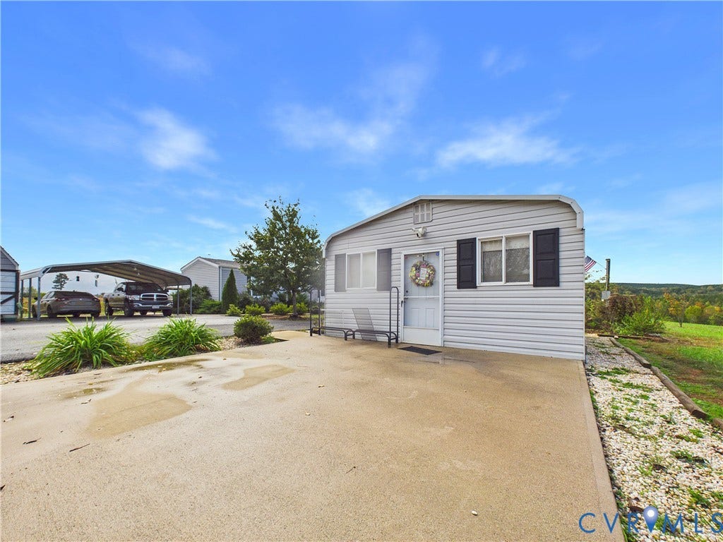 290 Western Lane, Appomattox, Appomattox, VA 24522 Exterior featuring light gray horizontal siding, dark decorative shutters, a concrete parking pad, and an attached metal-framed carport