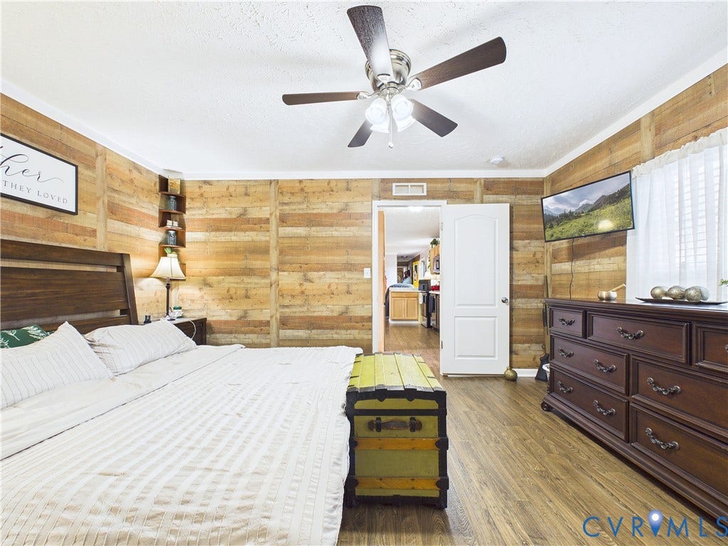 290 Western Lane, Appomattox, Appomattox, VA 24522 Interior room featuring horizontal wood-plank wall paneling, wood-finish flooring, a centrally mounted ceiling fan with integrated light fixture, and a white six-panel door