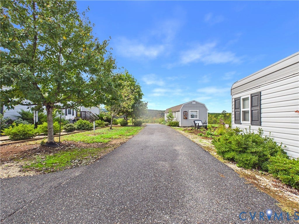 290 Western Lane, Appomattox, Appomattox, VA 24522 Asphalt driveway featuring a detached storage shed, exterior siding, mature trees, and landscaped shrubbery