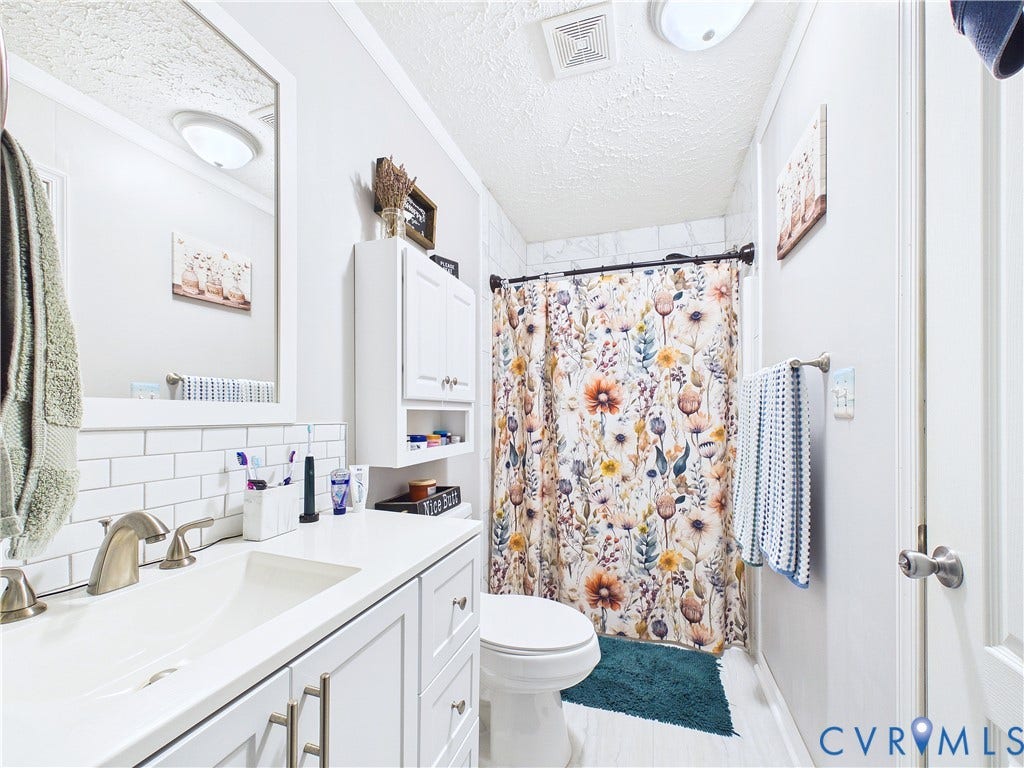 290 Western Lane, Appomattox, Appomattox, VA 24522 Bathroom featuring a white vanity cabinet with a solid-surface countertop, rectangular undermount sink, classic subway tile backsplash, and a wall-mounted storage cabinet
