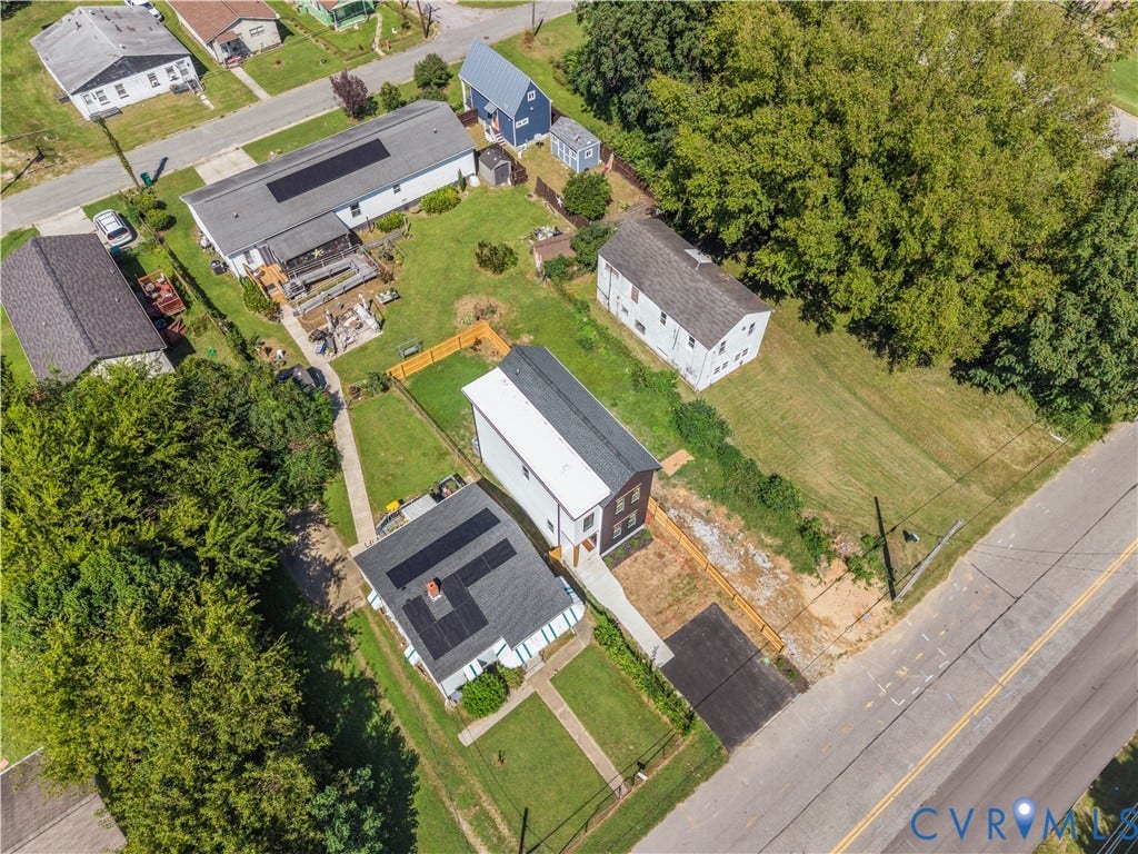851 E Bank Street, Old Towne, Petersburg, VA 23803 Aerial perspective featuring a multi-level structure with a metal roof, solar panel array, paved driveway, wood-fencing, and expansive lawn area