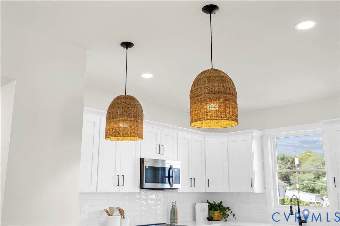851 E Bank Street, Old Towne, Petersburg, VA 23803 White Shaker-style cabinetry, stainless steel microwave, woven dome pendant lighting, white subway tile backsplash, and matte black faucet