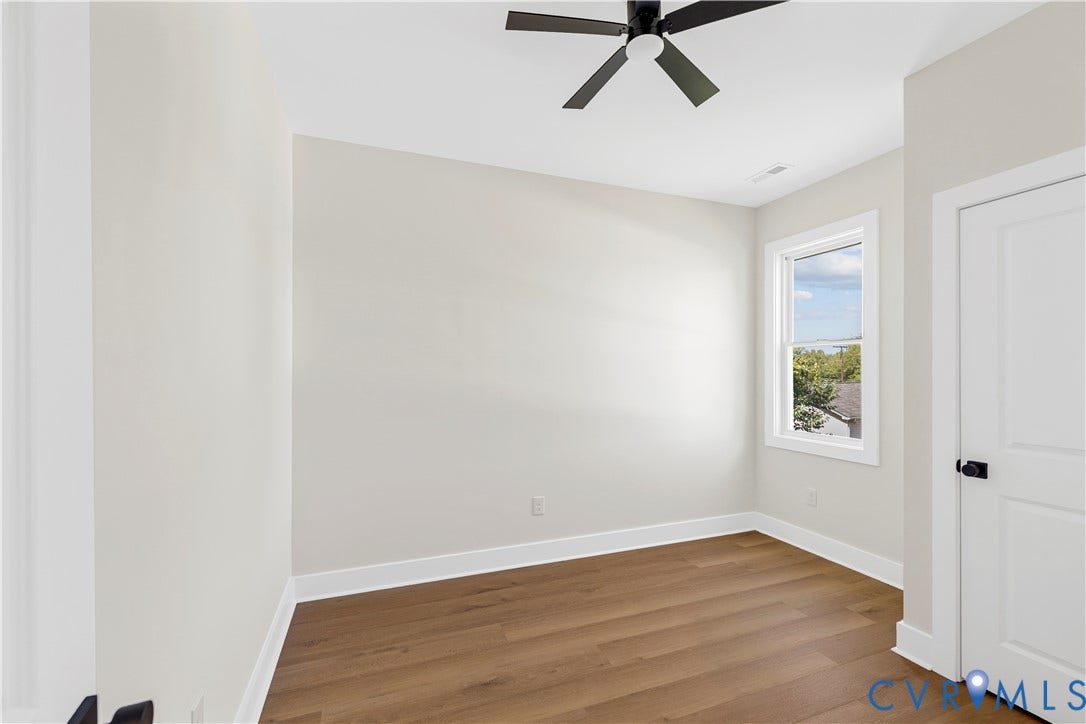 851 E Bank Street, Old Towne, Petersburg, VA 23803 Room featuring wood-finish flooring, neutral wall paint, a multi-blade ceiling fan, and a paneled interior door with matte black hardware