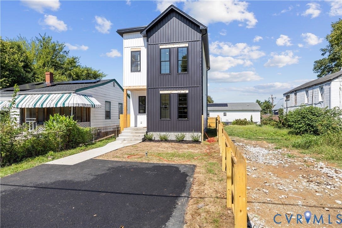 851 E Bank Street, Old Towne, Petersburg, VA 23803 Two-story exterior featuring a black metal panel facade, white vertical siding, concrete front steps, and an asphalt driveway