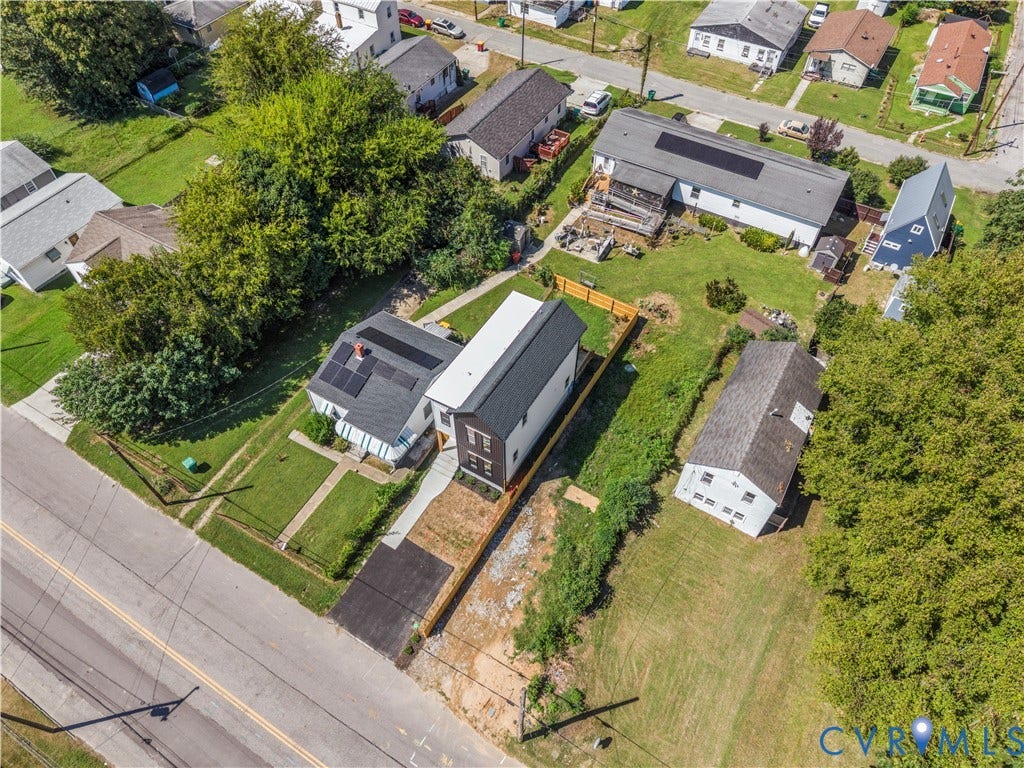 851 E Bank Street, Old Towne, Petersburg, VA 23803 Aerial perspective featuring a two-story residence with a dark metal roof, solar panel installation, asphalt driveway, and wood-style perimeter fencing