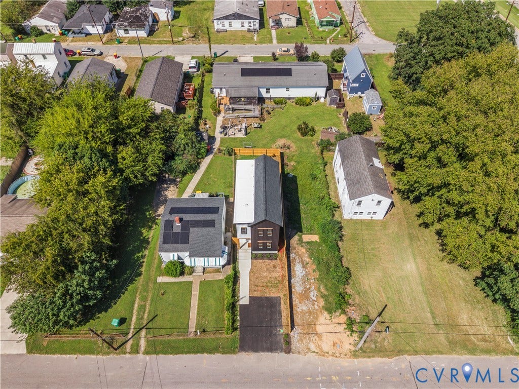 851 E Bank Street, Old Towne, Petersburg, VA 23803 Aerial view featuring a two-story residence with a dark metal roof, solar panels, a paved driveway, and a wood privacy fence