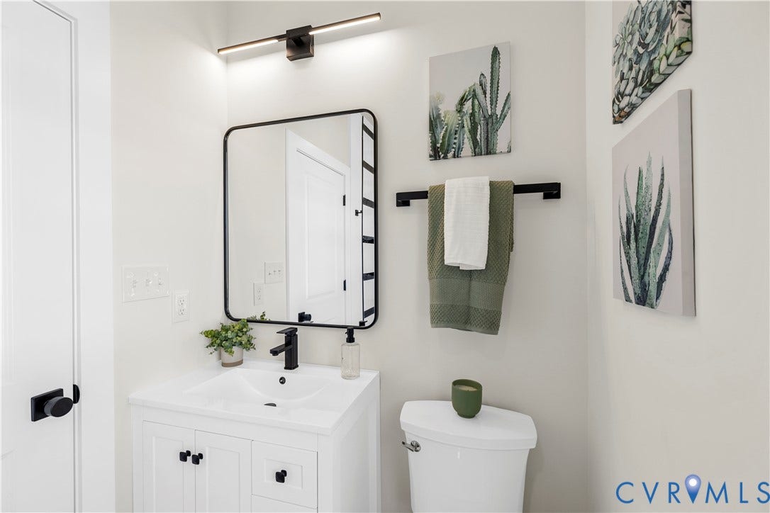851 E Bank Street, Old Towne, Petersburg, VA 23803 White cabinetry with integrated sink, rectangular mirror with black frame, matte black wall-mounted faucet, matching black light fixture, and coordinating black hardware