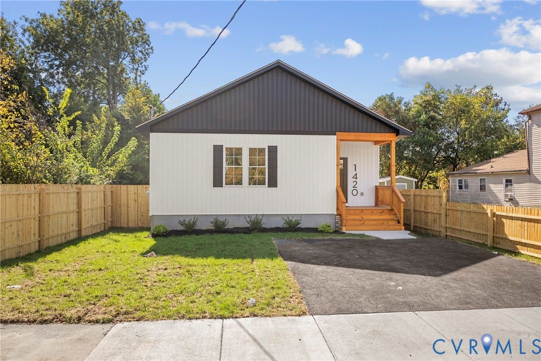 1420 Ferndale Avenue, Petersburg, VA 23803 Single-story residence featuring vertical siding, metal roof gable, wood-framed front porch, asphalt driveway, and enclosed perimeter fencing