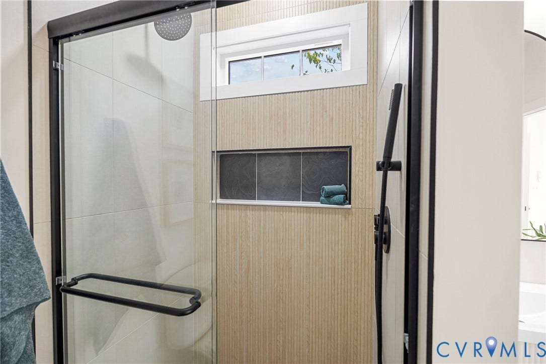 1420 Ferndale Avenue, Petersburg, VA 23803 Walk-in shower featuring a frameless glass door, matte black fixtures, rainfall showerhead, integrated tiled wall niche, and textured wood-finish tiling