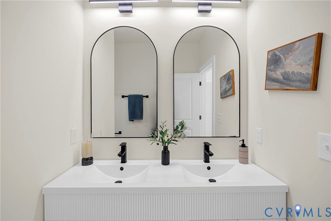 1420 Ferndale Avenue, Petersburg, VA 23803 Double vanity with white integrated dual sinks, textured fluted cabinetry, matte black wall-mounted faucets, and dual arched mirrors with black frames