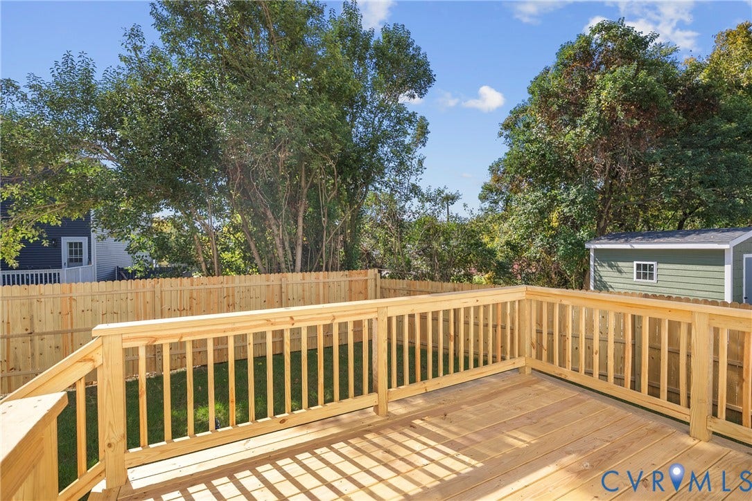 1420 Ferndale Avenue, Petersburg, VA 23803 Elevated wood deck featuring vertical baluster railings, wood fencing, and a detached storage structure