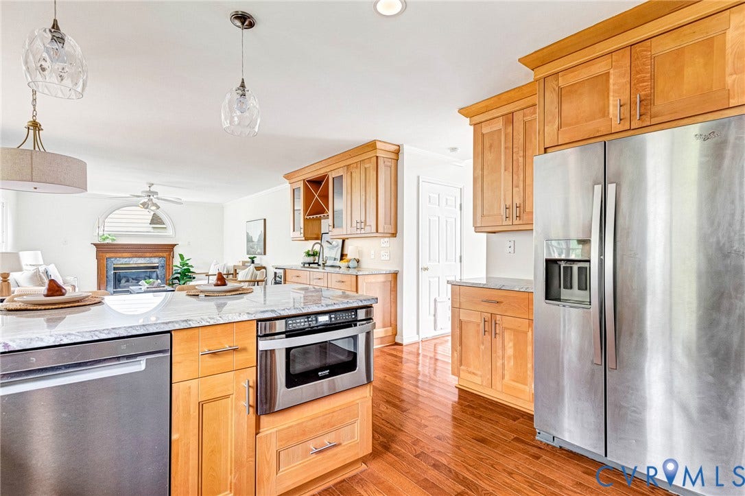 3629 Milbury Run Street, Henrico, VA 23233 Kitchen featuring light wood cabinetry, stone countertops, stainless steel appliances including a built-in microwave, wood-finish flooring, and multi-pendant lighting