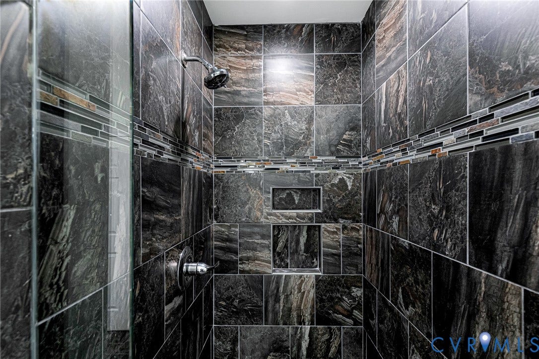3629 Milbury Run Street, Henrico, VA 23233 Walk-in shower featuring dark natural stone wall tile, decorative linear mosaic accent tile, integrated dual wall niches, and chrome fixtures