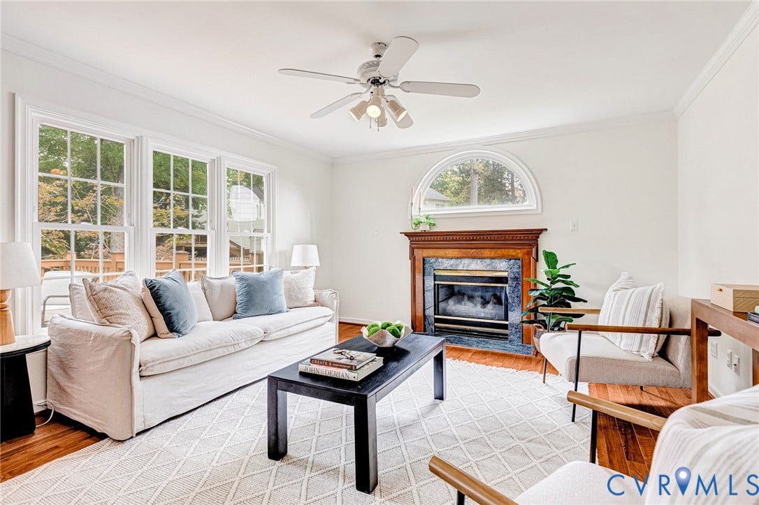 3629 Milbury Run Street, Henrico, VA 23233 Living area featuring wood-finish flooring, a fireplace with a decorative mantel and stone surround, an arched window, crown molding, and a multi-light ceiling fan