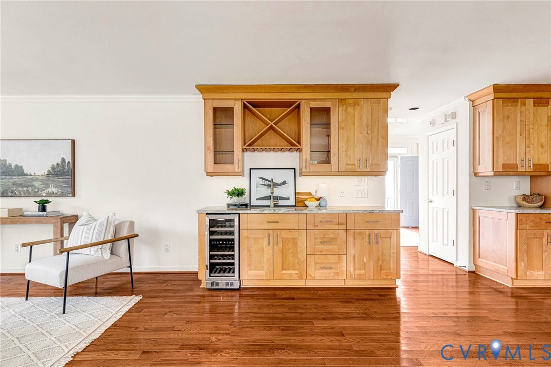 3629 Milbury Run Street, Henrico, VA 23233 Built-in wet bar featuring natural wood cabinetry, glass-paneled upper cabinets, integrated wine storage, and a stainless steel under-counter wine refrigerator, complemented by wood-finish flooring