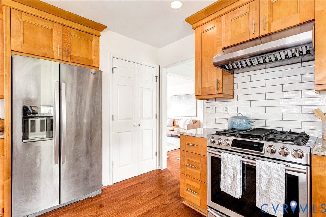 3629 Milbury Run Street, Henrico, VA 23233 Kitchen featuring custom wood cabinetry, stainless steel appliances, a professional-grade gas range with a matching range hood, a white subway tile backsplash, and wood-finish flooring