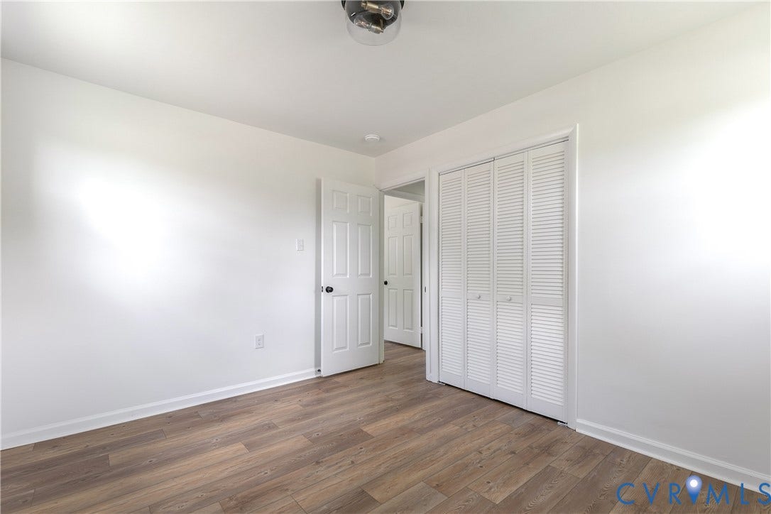 1809 Sussex Street, Whitcomb, Richmond, VA 23223 Room featuring wood-finish flooring, white walls, louvered bi-fold closet doors, and a flush-mount ceiling light fixture