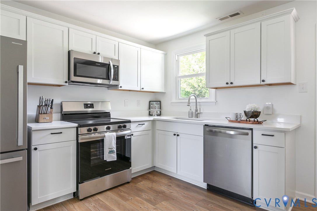 1809 Sussex Street, Whitcomb, Richmond, VA 23223 Kitchen featuring white shaker-style cabinetry, solid-surface countertops, wood-finish flooring, and stainless steel appliances