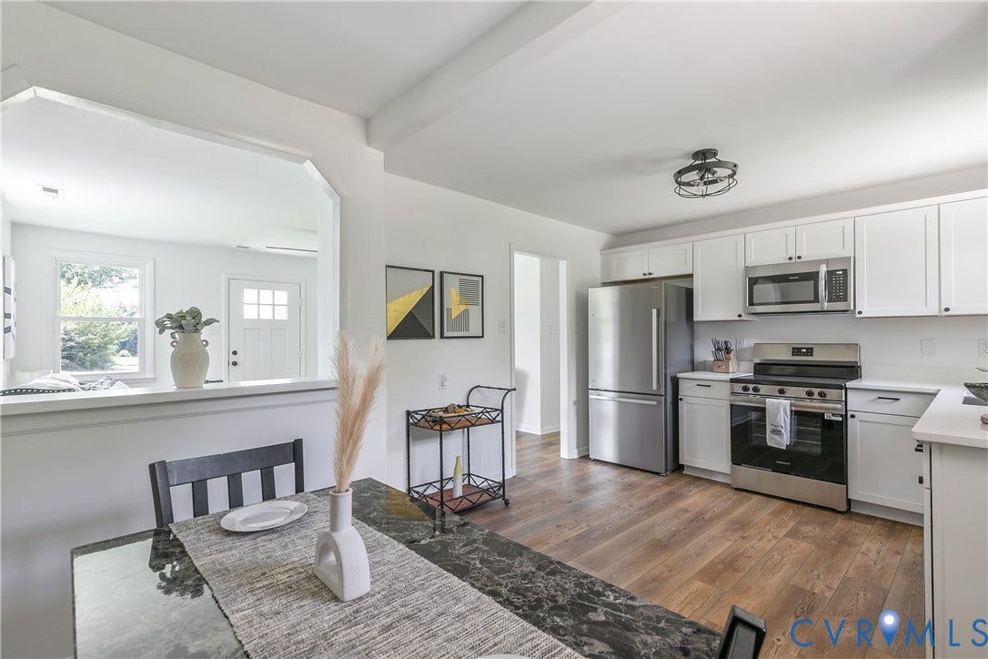 1809 Sussex Street, Whitcomb, Richmond, VA 23223 Kitchen featuring white cabinetry, stainless steel appliances, wood-finish flooring, and a pass-through opening