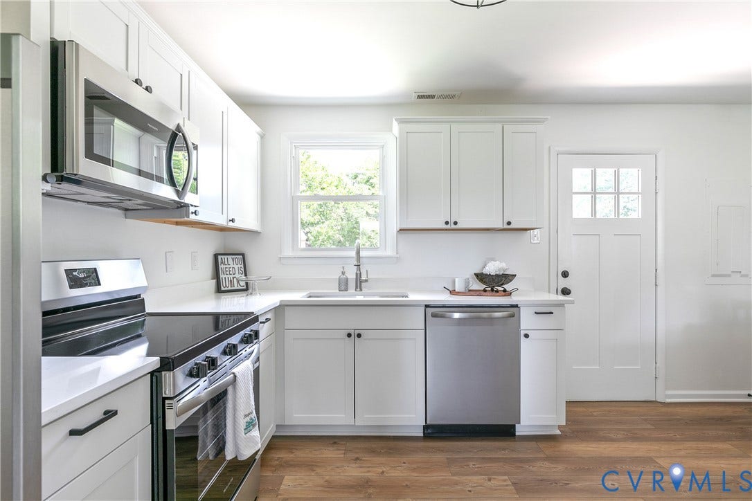 1809 Sussex Street, Whitcomb, Richmond, VA 23223 Kitchen featuring white Shaker-style cabinetry, stainless steel appliances, wood-finish flooring, solid-surface countertops, and a six-pane glass inset door