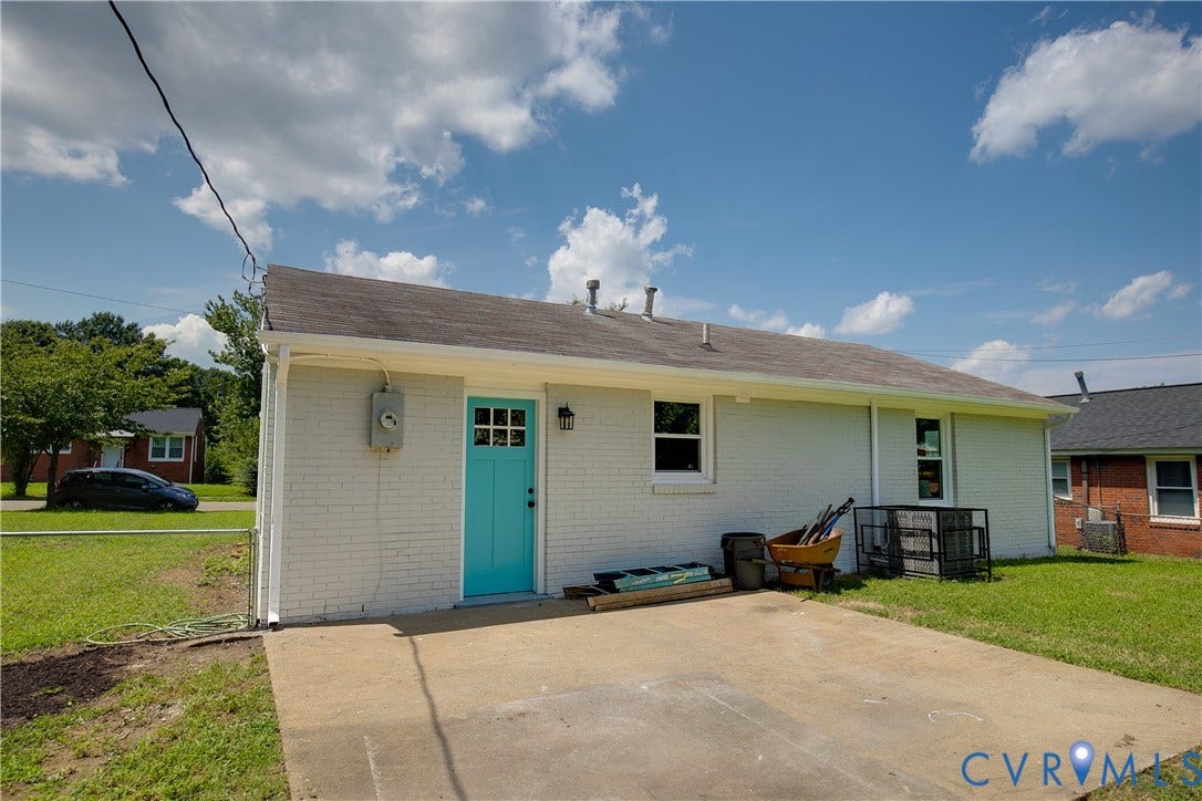 1809 Sussex Street, Whitcomb, Richmond, VA 23223 Exterior view featuring a white painted brick facade, a concrete patio, and a bold-colored paneled entry door